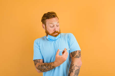 Afraid man with beard, tattoo and mask  ready for the virus vaccine