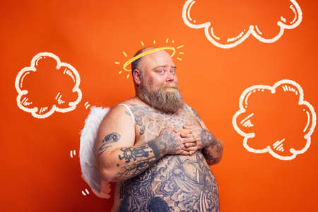 Fat man with beard ,tattoos and wings acts like an angelの写真素材