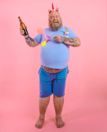 Fat happy man acts like a happy baby but drinks beerの写真素材