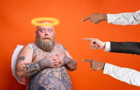 Fat afraid man with beard ,tattoos and wings acts like an angelの写真素材