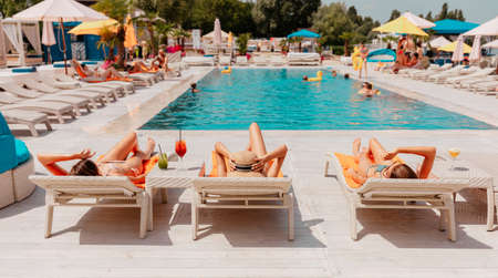 Group of friends in swimsuit drink a cocktail in a swimming poolの写真素材
