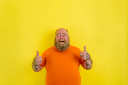 Happy man with beard and tattoos does a positive gesture with handsの写真素材