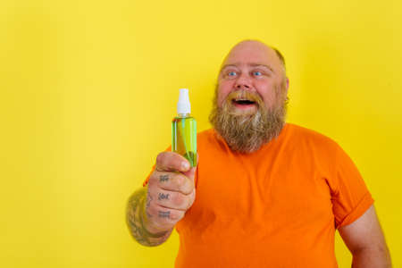 Happy man with beard and tattoos holds a hands cleaner against virusの写真素材
