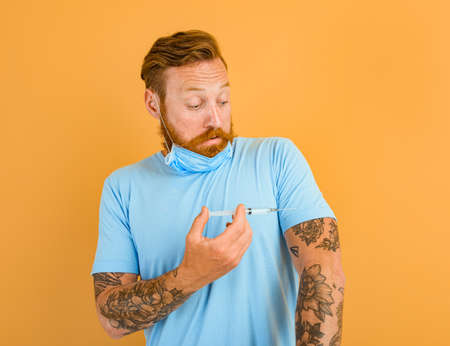 Afraid man with beard, tattoo and mask for covid-19 is ready for the virus vaccine