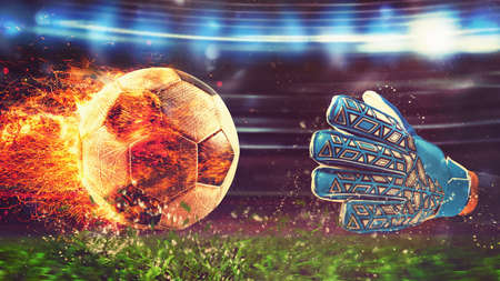 Close up of a soccer scene at night match with a goalkeeper trying to catch a fiery ballの写真素材