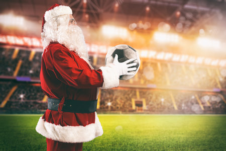 Santa Claus with a soccer ball in his hands inside a soccer stadiumの写真素材