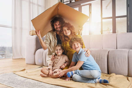 Happy family play together under a cardboard roofの写真素材