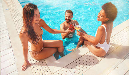 Group of friends with swimsuit drink a cocktail in a beach place