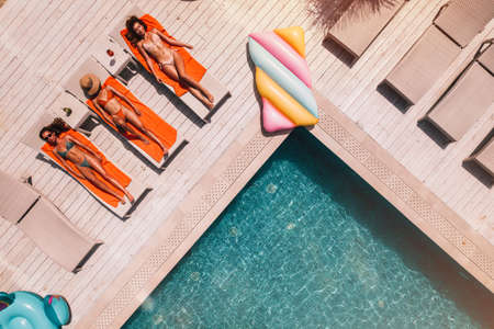 Group of friends in swimsuit drink a cocktail in a swimming poolの写真素材