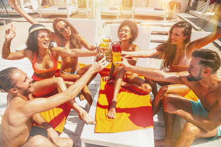 Group of friends with swimsuit drink a cocktail in a beach placeの写真素材