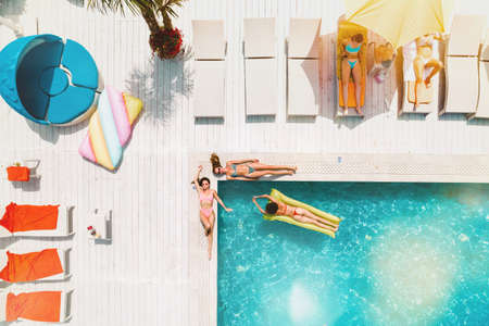 Friends in swimsuit who tan in the sunbed in a swimming poolの写真素材