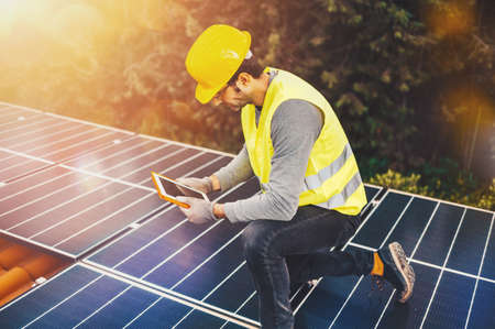 Workers verify energy system with solar panel with a tablet