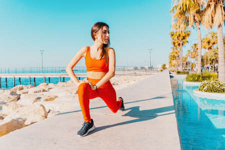 Woman does gym stretching exercises outdoor in a sunny day