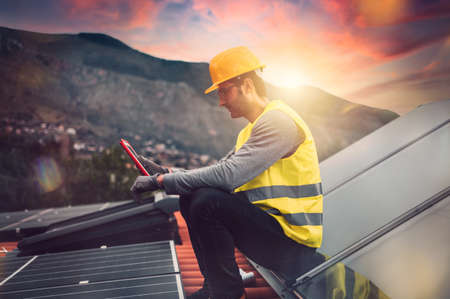 Man works on renewable energy system with solar panel for electricity and hot water