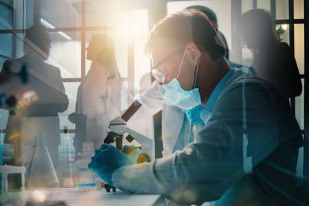Doctor in the laboratory analyzes samples of codiv-9 under a microscopeの写真素材