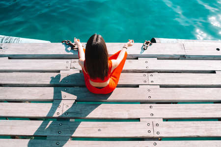 Woman relaxing in yoga position in the summer in front of the seaの写真素材