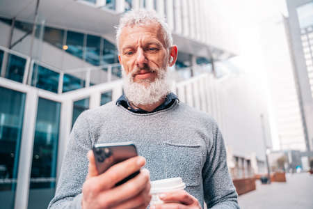 Businessman out of the office reads email from smartphone