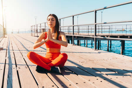 Woman relaxing in yoga position in the summer in front of the sea