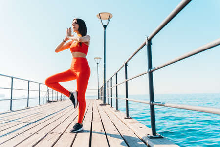 Woman relaxing in yoga position in the summer in front of the seaの写真素材