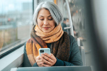 Senior woman send message with a mobile phone in a trainの写真素材