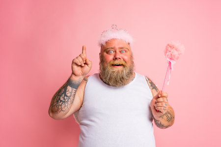 Fat man with tattoos and beard acts like a magic fairyの写真素材