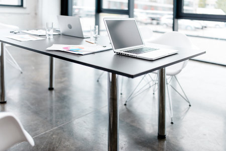 Modern office with graph sheets and laptop on a deskの写真素材