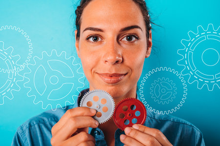 Happy woman joins pieces of gears as concept of partnership and integrationの写真素材