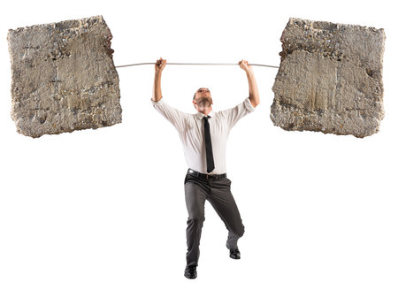 Powerful and determined businessman trains with a barbell with stonesの写真素材