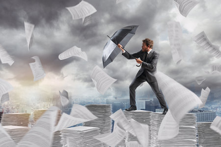 Businessman cover himself from a bureaucracy storm with an umbrellaの写真素材