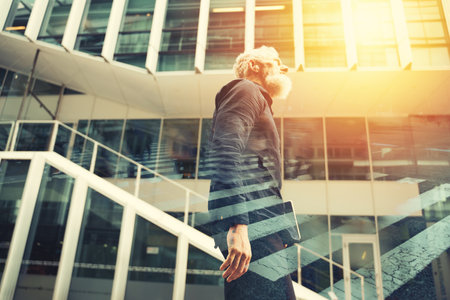 Senior business man with beard walks in front of a modern officeの写真素材