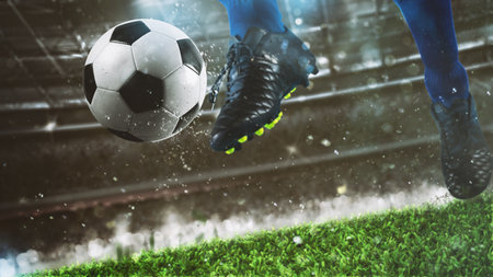 Football scene at night match with close up of a soccer shoe hitting the ball with powerの写真素材