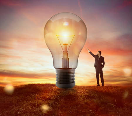 Businessman indicates a big light bulb as idea, resolution and creativity conceptの写真素材