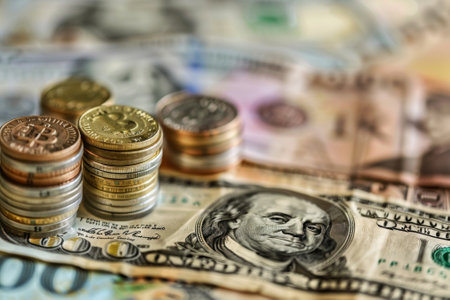 Close-up image of stacked coins on assorted currency bills conveying financial growth and investmentの素材
