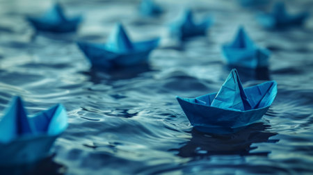 One blue paper boat leading a fleet on water represents leadership, teamwork, and guidanceの素材