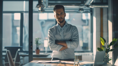 Efficient professional man with crossed arms in modern office settingの素材