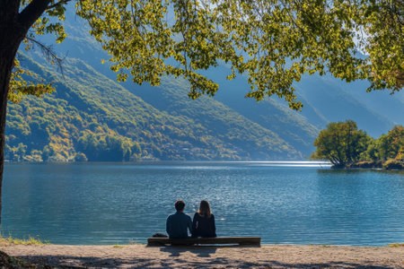 Couple relaxing on bench enjoying lake view in the fallの素材
