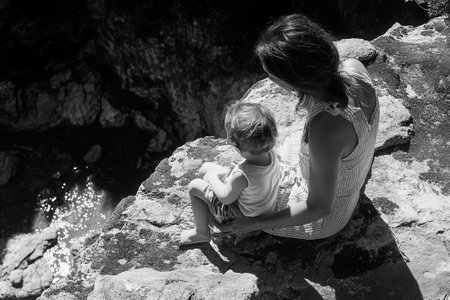 Mother and child admiring breathtaking scenery from rocky cliffの素材