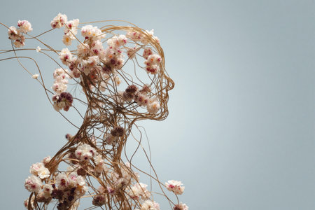 Sculpture of a human figure entwined with flowers and vines in a minimalist settingの素材