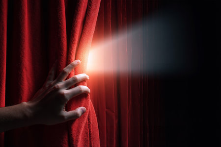 Hand pulling a red velvet curtain to reveal a bright light shining through a crackの素材