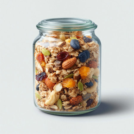 Colorful layers of granola and dried fruits in a transparent glass jar on a clean surfaceの素材
