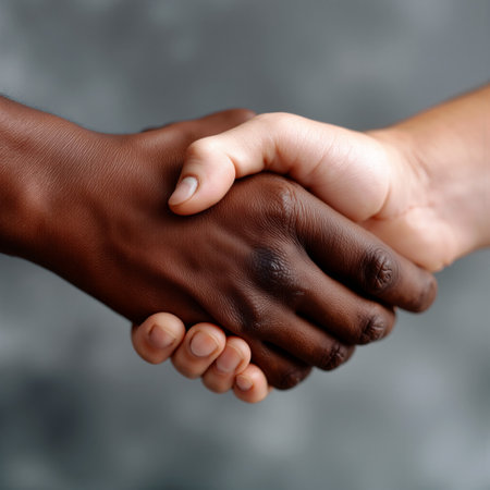 Handshake between business partners representing unity and collaboration in a diverse workplace settingの素材