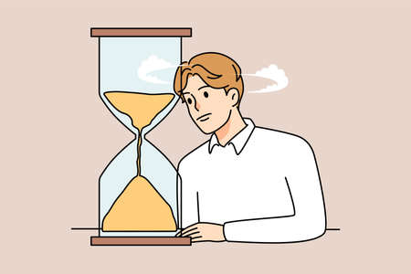 Bored man look at hourglass waiting