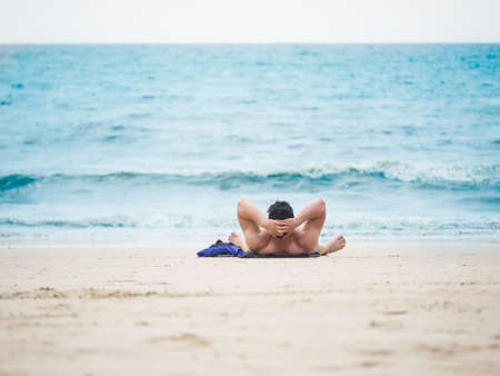 Man laying on the beach enjoying summer holidays looking at the oceanの写真素材