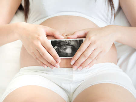 Women holding smartphone which show baby inside
