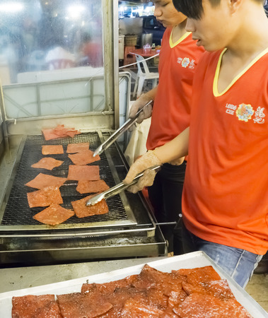 KUALA LUMPUR, MALAYSIA - AUGUST 29: Shop workers grilling dried pork meat in Jalan Alor Chinatown, Kuala Lumpur on August 29, 2014. Very famous among locals and touristsのeditorial素材