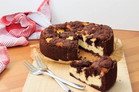 Cheesecake with chocolate shortcrust pastry and chocolate crumble arranged on a wooden boardの写真素材