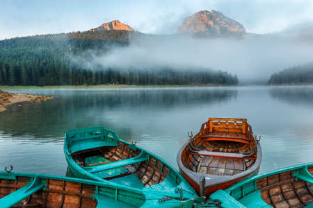 Morning landscape with mountains, lake and boatの写真素材