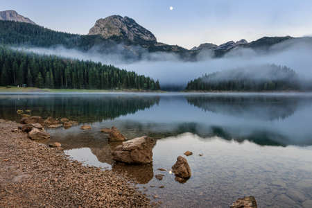 Morning mist over black lake and durmitor mountainの写真素材