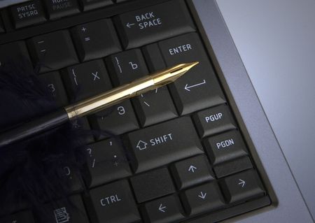 golden feather quill on laptopの写真素材