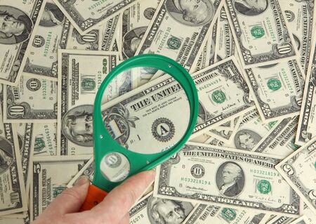 Dollars and magnifier in hand
